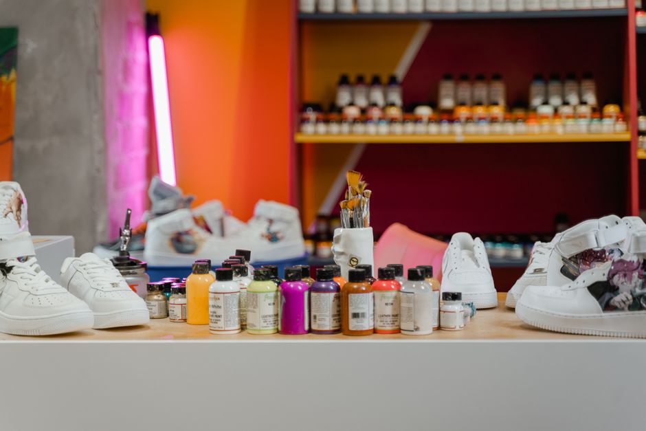 Vibrant art studio showcasing white sneakers, paints, and brushes for creative projects.
